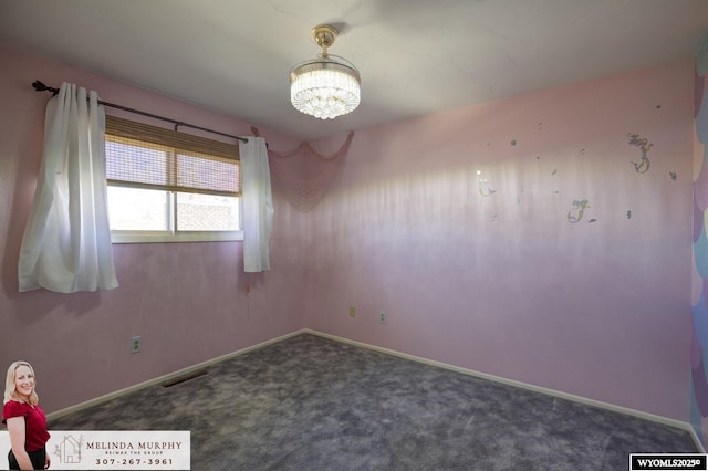 carpeted spare room with visible vents, baseboards, and an inviting chandelier