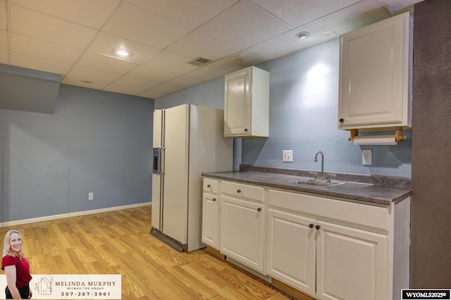 kitchen with a drop ceiling, light wood-style flooring, a sink, visible vents, and dark countertops