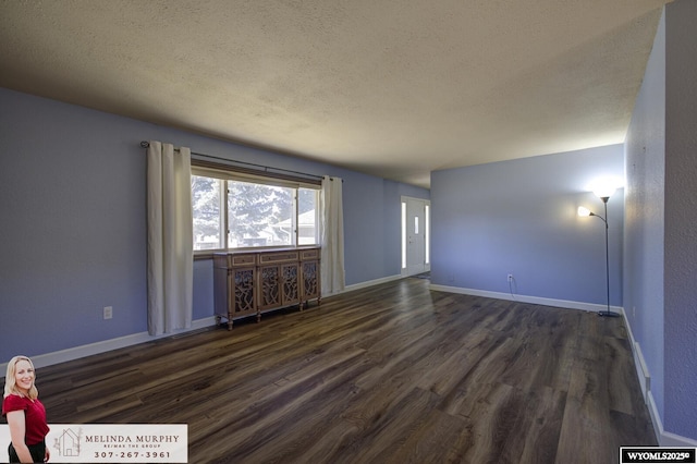 empty room with dark wood-style floors, baseboards, and a textured ceiling