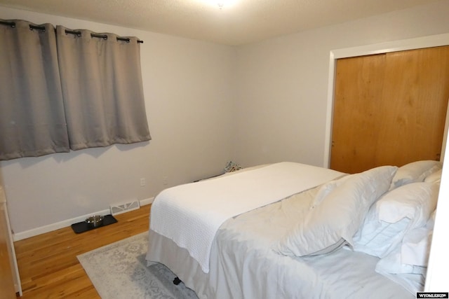 bedroom with visible vents, baseboards, and wood finished floors