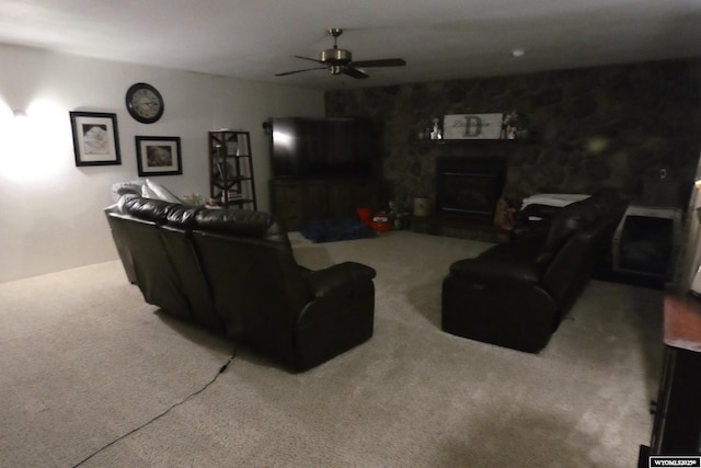 carpeted living room featuring a ceiling fan and a fireplace with raised hearth