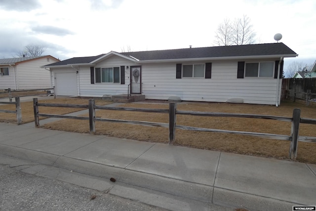 ranch-style house featuring an attached garage and a fenced front yard