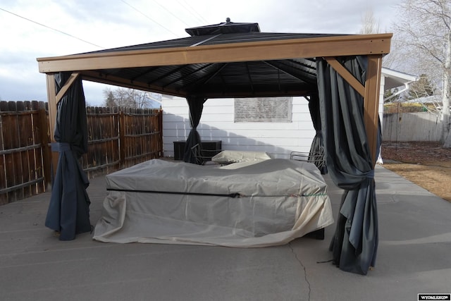 view of parking featuring a carport, fence, and a gazebo