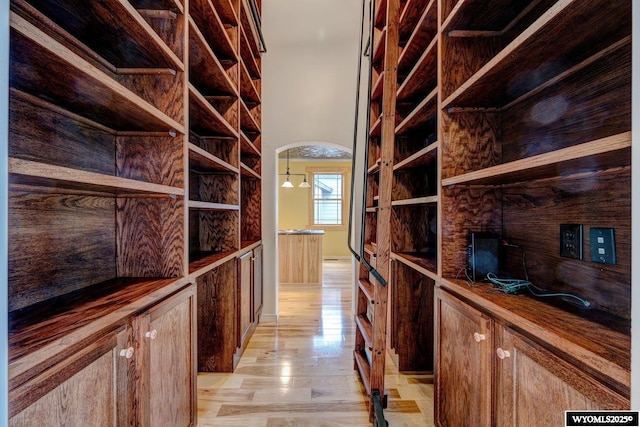 wine cellar featuring light wood-style flooring, a high ceiling, and arched walkways