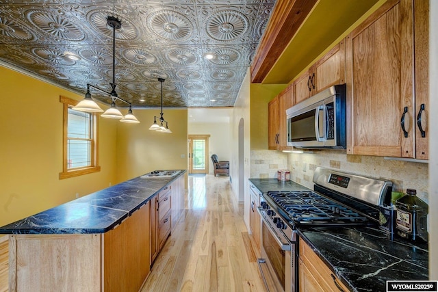 kitchen with arched walkways, light wood-style flooring, appliances with stainless steel finishes, decorative backsplash, and an ornate ceiling