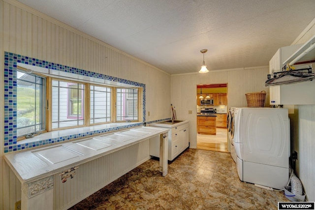 laundry area featuring washer / dryer, plenty of natural light, laundry area, and crown molding