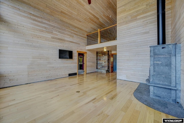 unfurnished living room with a towering ceiling, wooden walls, and wood finished floors