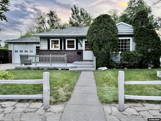 ranch-style home featuring an attached garage, a yard, roof with shingles, and brick siding