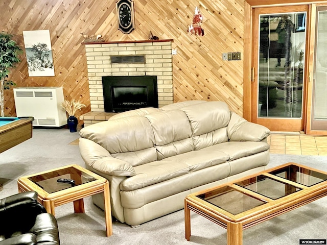 living area with heating unit, a brick fireplace, carpet flooring, and wood walls