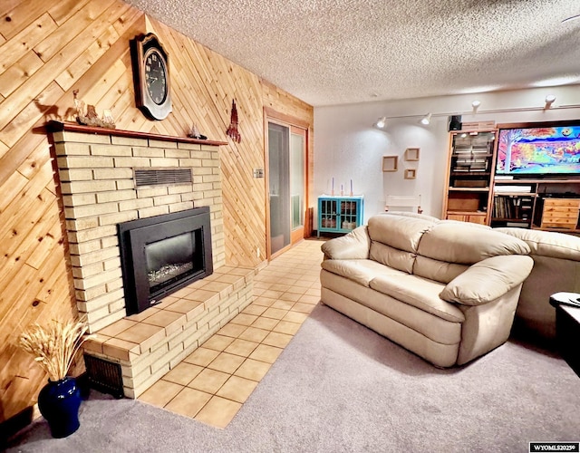 living area with tile patterned flooring, a brick fireplace, wood walls, and a textured ceiling