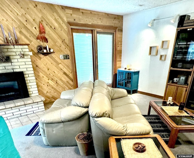 living room featuring a textured ceiling, a brick fireplace, baseboards, and wooden walls