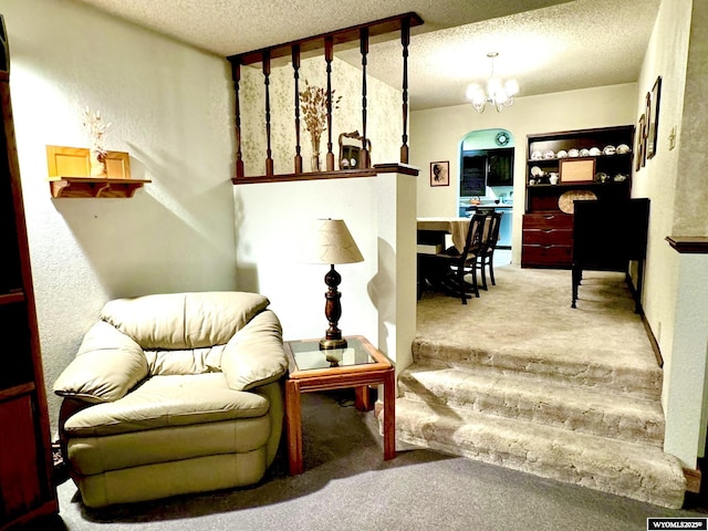 living area with a chandelier, carpet, a textured wall, and a textured ceiling