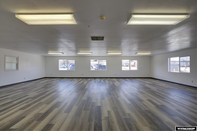 spare room featuring wood finished floors, visible vents, and a healthy amount of sunlight