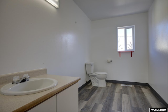 bathroom with toilet, wood finished floors, visible vents, vanity, and baseboards