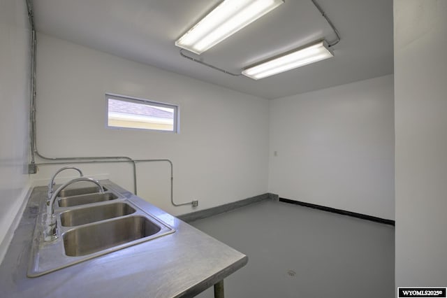 kitchen with finished concrete flooring, baseboards, and a sink