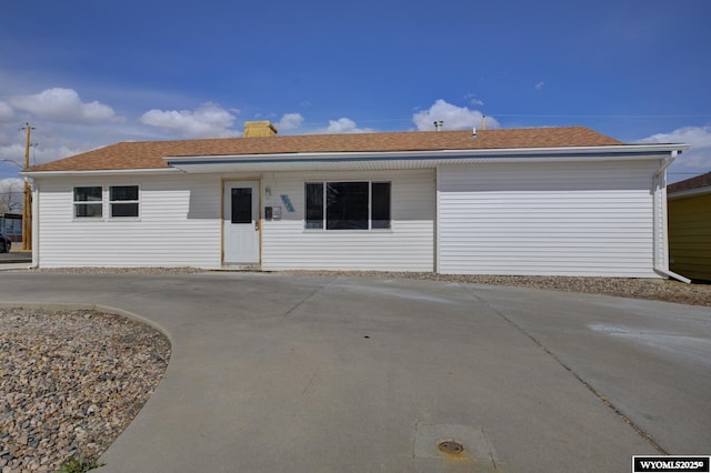 ranch-style home with concrete driveway and roof with shingles