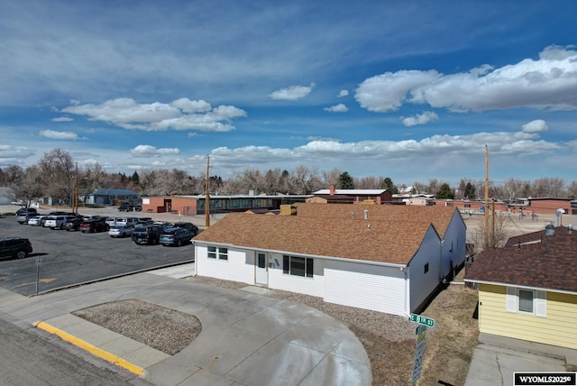 view of front facade with uncovered parking and a shingled roof