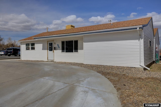 back of property featuring driveway and a shingled roof