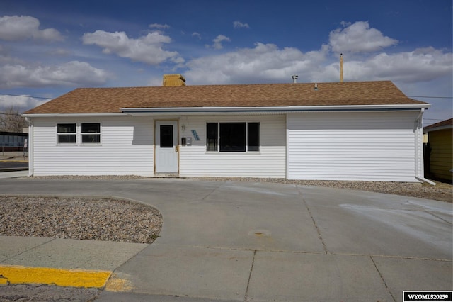 ranch-style house with driveway, a chimney, and roof with shingles