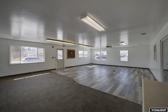 empty room with a healthy amount of sunlight, visible vents, and wood finished floors