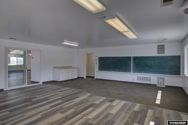 unfurnished living room featuring visible vents and wood finished floors