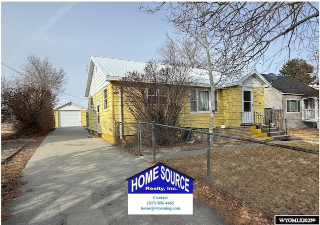 view of front of house with a garage, metal roof, a fenced front yard, and an outdoor structure