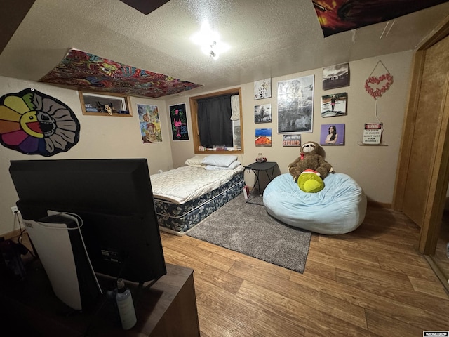 bedroom with a textured ceiling and wood finished floors