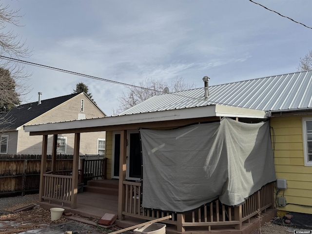 back of house featuring a deck, fence, and metal roof