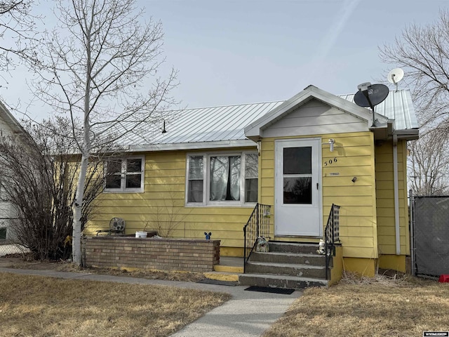 view of front of property with entry steps, fence, and metal roof