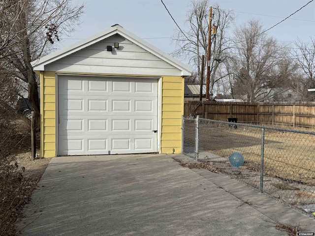 detached garage featuring fence and driveway