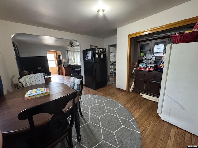 dining room featuring arched walkways, ceiling fan, and wood finished floors