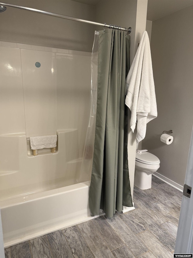 bathroom with toilet, shower / bathtub combination with curtain, baseboards, and wood finished floors