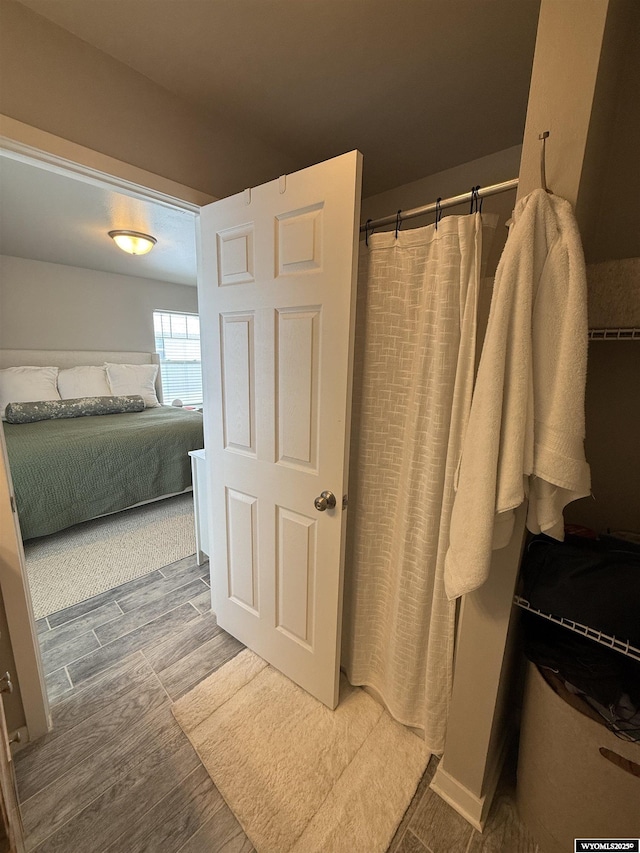 ensuite bathroom with a shower with shower curtain, connected bathroom, and wood finish floors