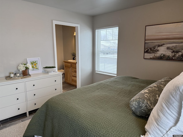 bedroom featuring ensuite bath and wood finished floors