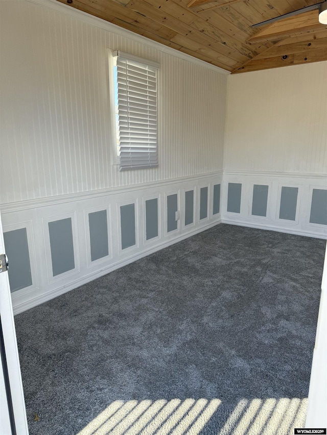 empty room featuring carpet floors, wood ceiling, and vaulted ceiling