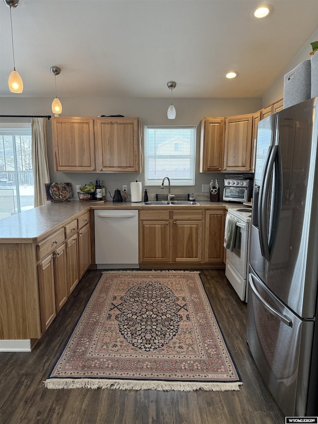 kitchen with dark wood-style flooring, light countertops, a sink, white appliances, and a peninsula