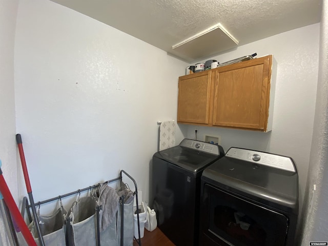 clothes washing area featuring cabinet space, a textured ceiling, and washing machine and clothes dryer