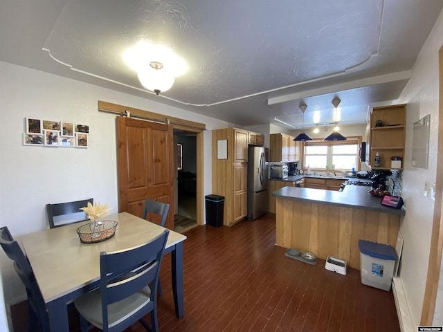 kitchen featuring dark wood-style floors, open shelves, a barn door, freestanding refrigerator, and a peninsula