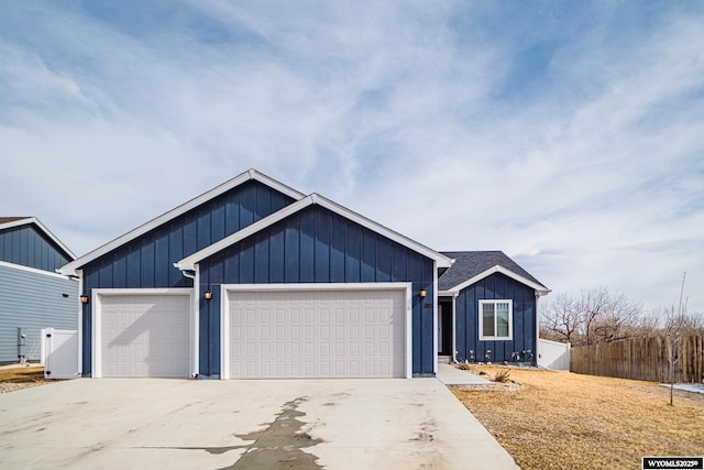 view of front of property with concrete driveway, board and batten siding, an attached garage, and fence