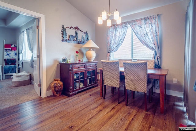 dining space featuring lofted ceiling, a notable chandelier, baseboards, and wood finished floors