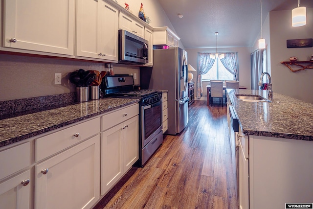 kitchen with stainless steel appliances, dark stone counters, a sink, white cabinetry, and dark wood-style floors