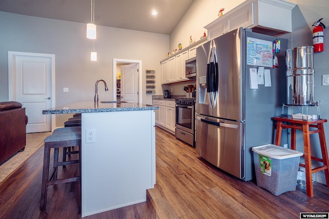 kitchen featuring a breakfast bar area, a sink, appliances with stainless steel finishes, dark wood finished floors, and a center island with sink