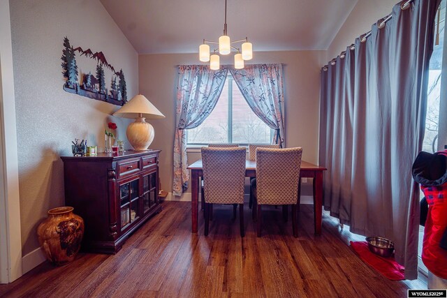 dining area with a chandelier, wood finished floors, lofted ceiling, and baseboards