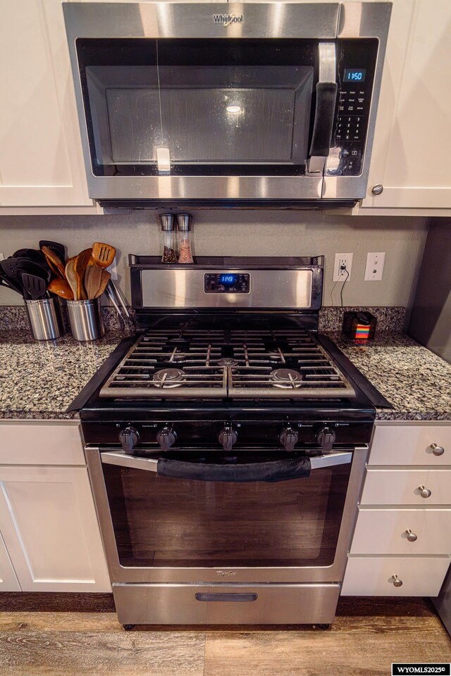 kitchen with appliances with stainless steel finishes, white cabinets, and dark stone countertops