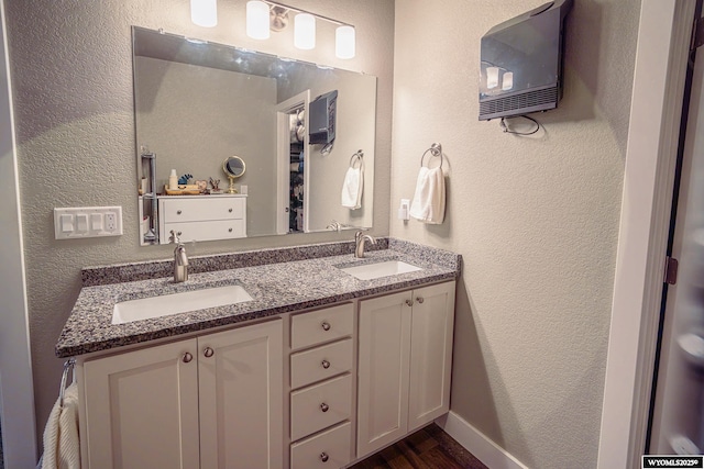 bathroom featuring double vanity, a sink, and a textured wall