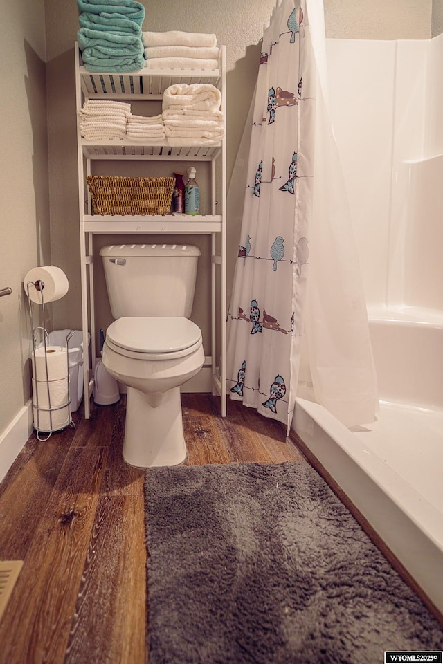 bathroom with baseboards, toilet, and wood finished floors