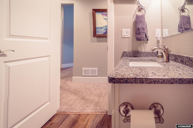 bathroom featuring vanity, wood finished floors, visible vents, and baseboards