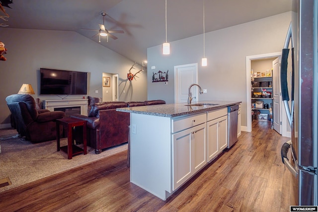 kitchen featuring stainless steel appliances, wood finished floors, a sink, white cabinetry, and open floor plan