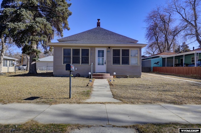 bungalow with roof with shingles, a chimney, and fence