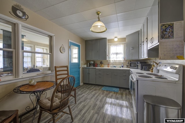 kitchen with electric stove, decorative light fixtures, light countertops, gray cabinetry, and light wood-style floors